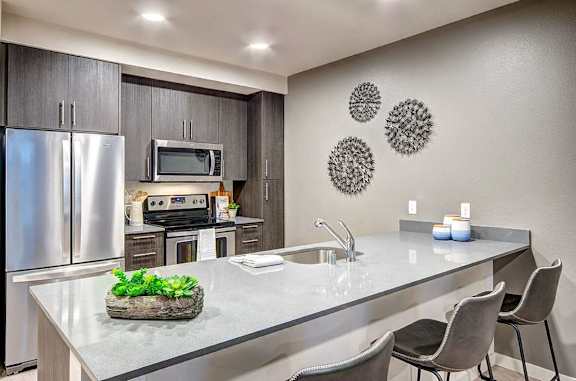 A modern kitchen with a stainless steel refrigerator, microwave, and oven.