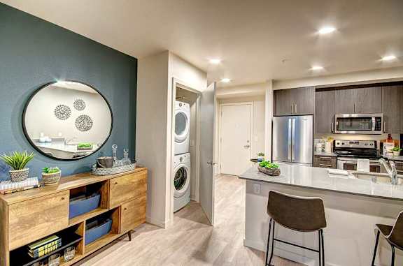 A modern kitchen with a wooden drawer and a round mirror above it.