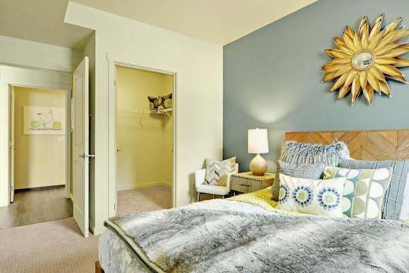 A bedroom with a bed, nightstand, and a wall hanging sunflower.