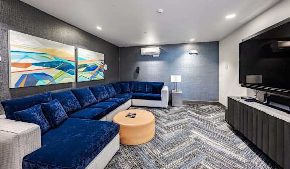 A modern living room with a blue velvet sofa and a television.