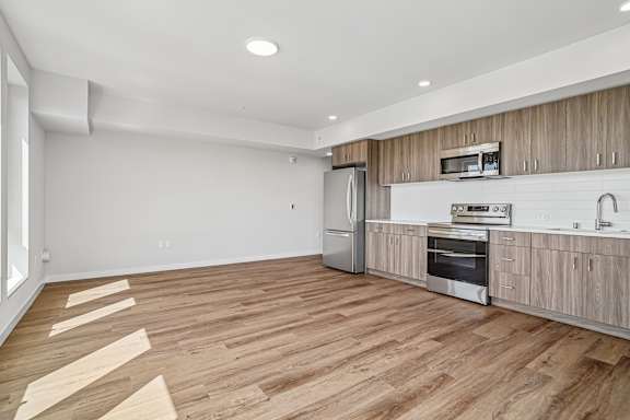 A kitchen with wooden floors and a stainless steel refrigerator.