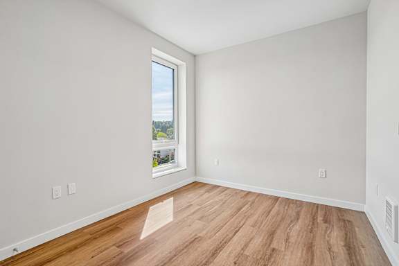 A room with a window and wooden flooring.