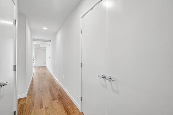 A long hallway with white walls and wood floors.