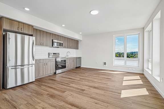 A modern kitchen with wooden cabinets and a stainless steel refrigerator.
