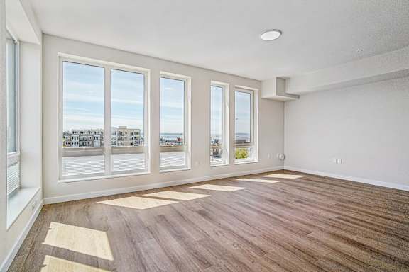 A room with wooden flooring and large windows overlooking a cityscape.