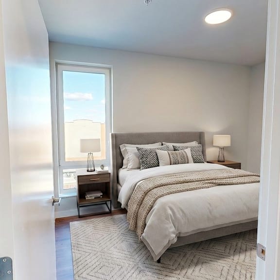 A bedroom with a large bed and a view of the city through the window.