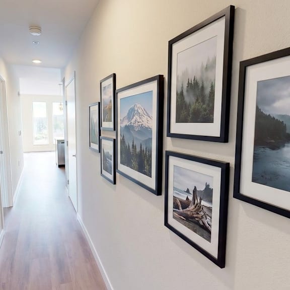 A hallway with a series of framed pictures on the wall.