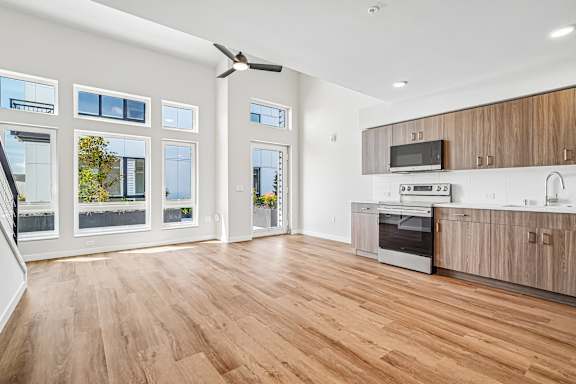 A modern kitchen with wooden floors and stainless steel appliances.