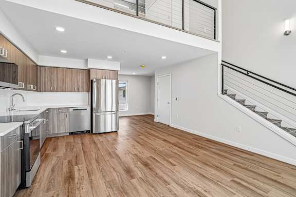 A modern kitchen with wooden floors and stainless steel appliances.