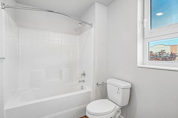 A white toilet sits next to a white bathtub in a bathroom.