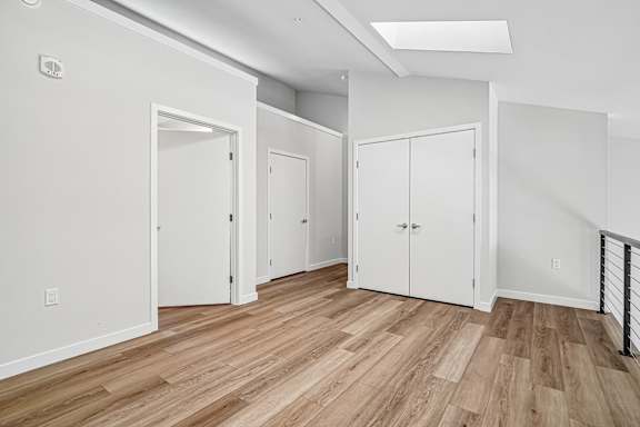 A room with white walls and wood flooring with three white doors.