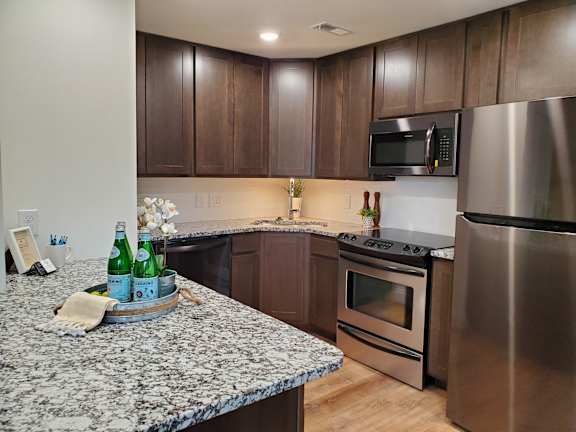 A kitchen with a granite countertop and stainless steel appliances.