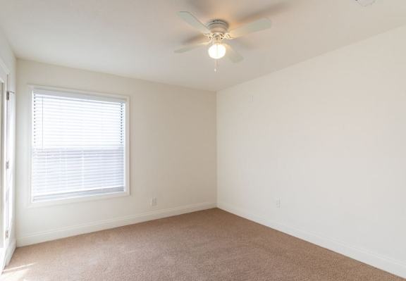 A room with a ceiling fan and carpeted floor.
