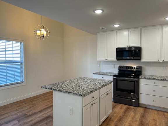 A kitchen with a granite countertop and white cabinets.