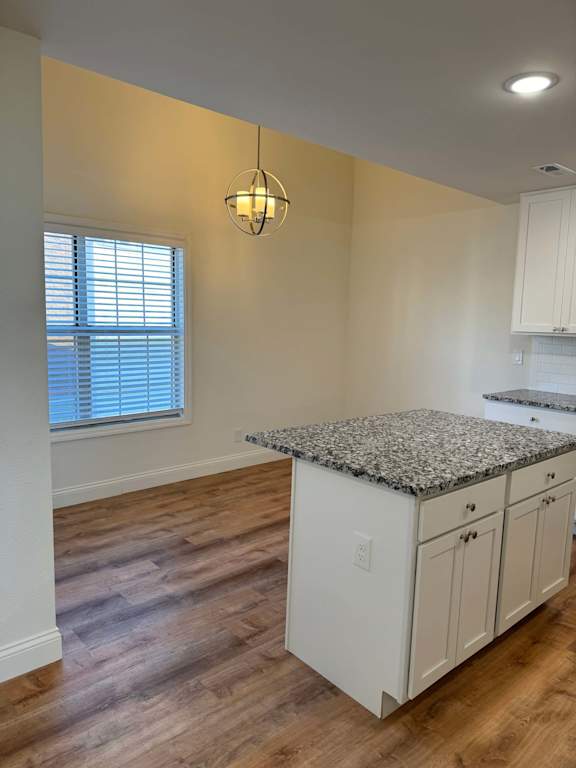 A kitchen with white cabinets and a granite countertop.