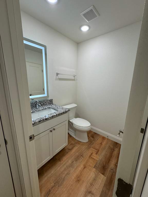 A small bathroom with a toilet, sink and mirror.