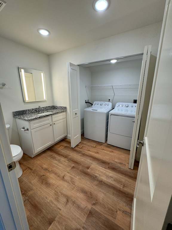 A small bathroom with a toilet, sink, and a laundry area.