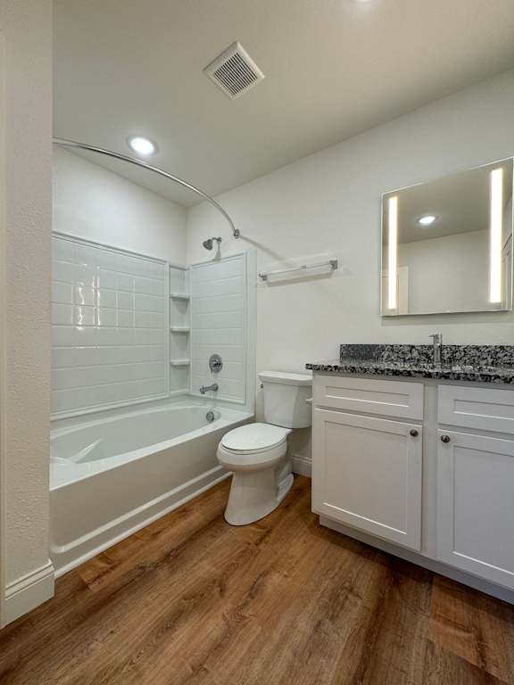 A white bathroom with a wooden floor and a white tub.
