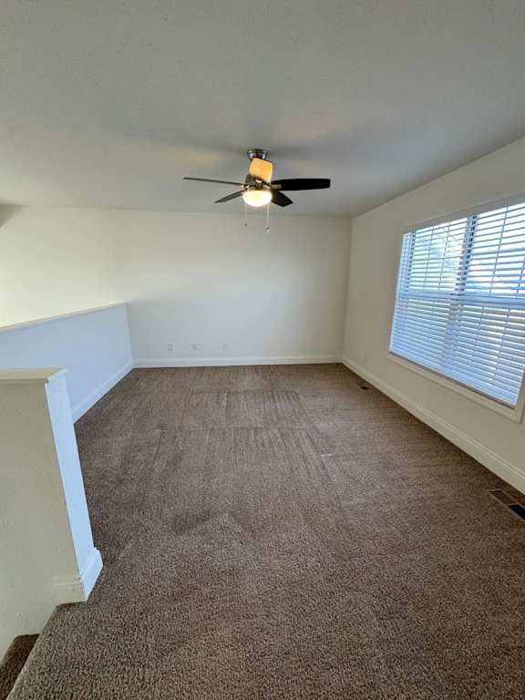 A room with a ceiling fan and carpeted floor.