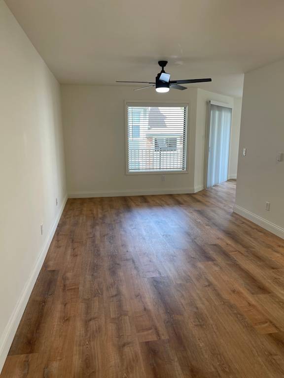A room with wooden flooring and a ceiling fan.