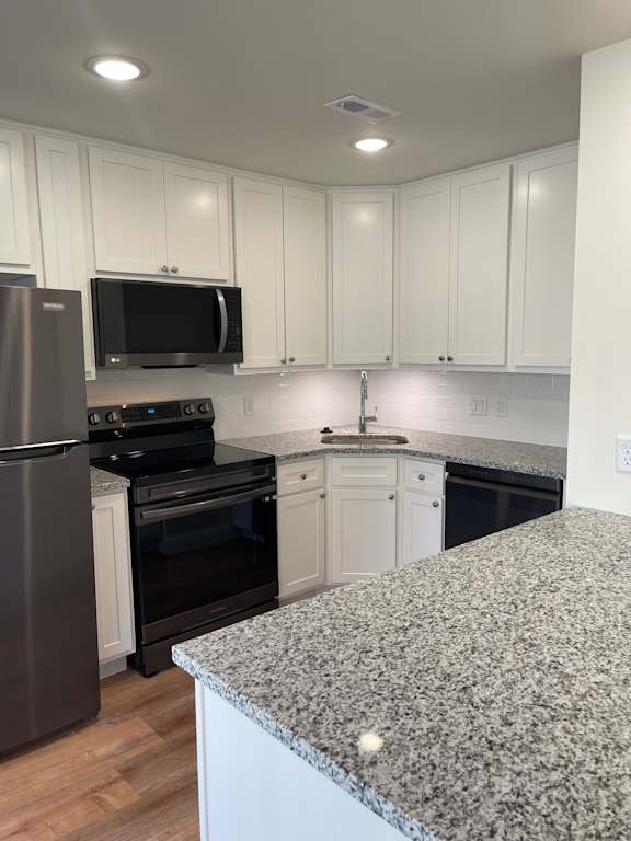 A kitchen with white cabinets and a granite counter.