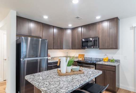 A kitchen with a granite countertop and stainless steel appliances.