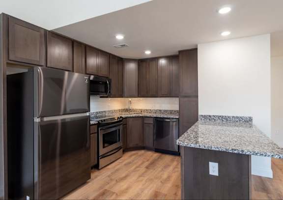 A kitchen with a granite counter top and stainless steel appliances.
