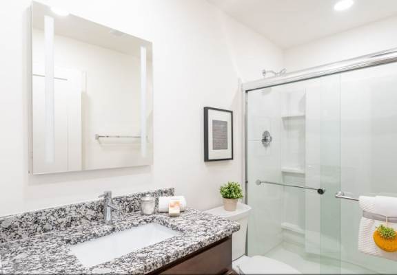 A bathroom with a marble countertop and a glass shower.