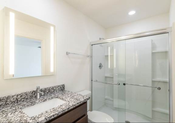 A bathroom with a sink, mirror, and shower.