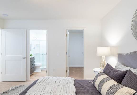 A bedroom with a bed, pillows, and a lamp.