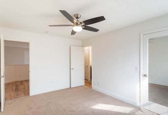 A room with a ceiling fan and carpeted floor.