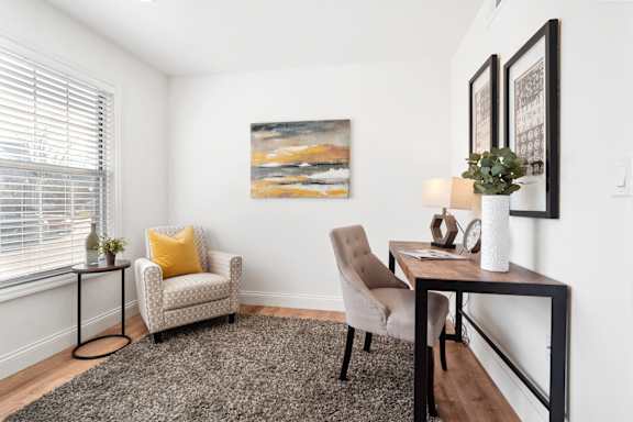 A living room with a chair, a table, and a painting on the wall.