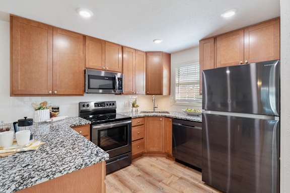A kitchen with wooden cabinets and a granite countertop.