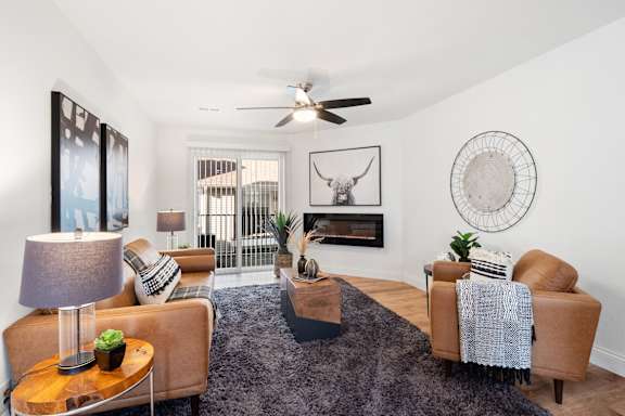 A living room with a fireplace and a fan on the ceiling.