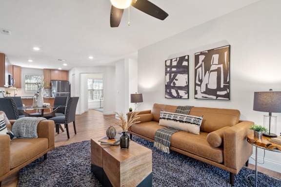 A living room with a brown couch and a ceiling fan.