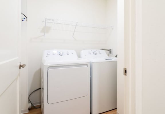 Two white front loading washing machines in a small laundry room.
