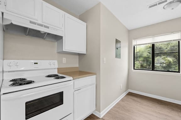 A white stove and oven in a kitchen with a window.