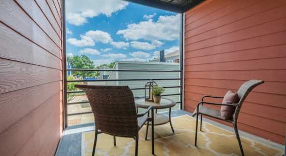 A balcony with a chair and table overlooking a building. at Infinity on the Landing Apartments , Texas, 76040