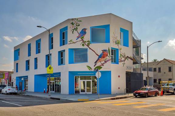 A blue and white building with a mural of a bird on it.at Catalina West Adams, Los Angeles California