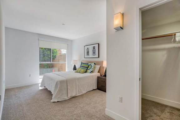 A bedroom with a bed, pillows, and a window.
