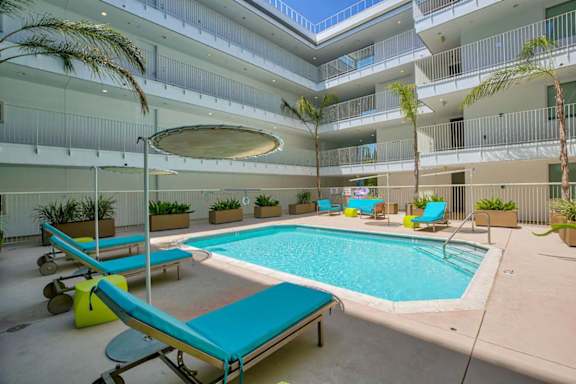 A large indoor pool with lounge chairs and palm trees.