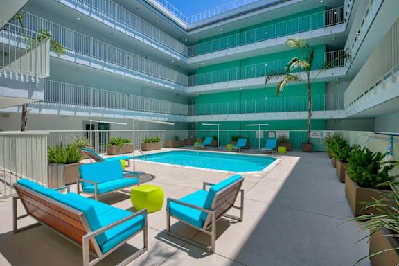 A pool area with blue chairs and a yellow ottoman.