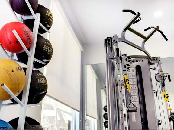A gym with a weight rack and exercise balls.