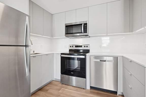 A modern kitchen with stainless steel appliances and white cabinetry.at The Wilson, Santa Monica California