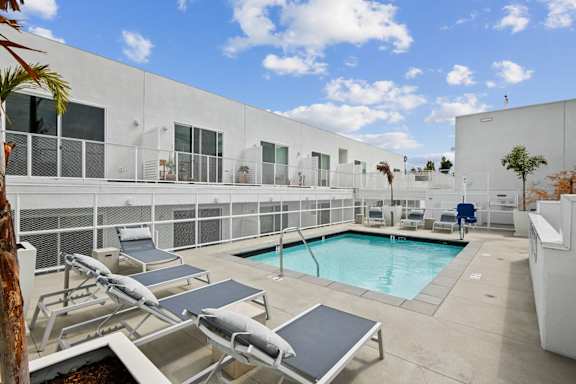 A pool area with sun loungers and a white building in the background.at The Dillon II at Silver Lake, California