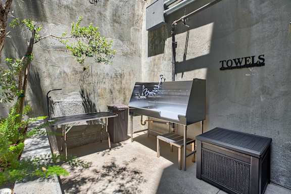 A small outdoor kitchen area with a grill and a table.at The Dillon, California, 90026