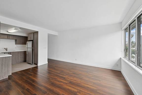 A kitchen with a refrigerator, sink, and wooden floors.