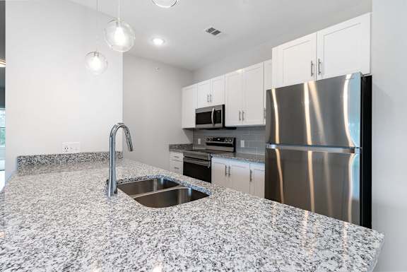 A kitchen with a granite countertop and stainless steel appliances at The Banks at Bridgewater Apartments, South Carolina