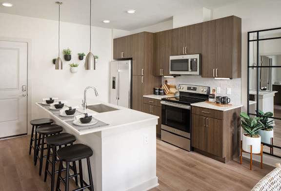A modern kitchen with a white island and dark brown cabinets.