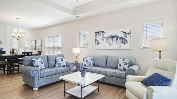 A living room with a grey couch, a white armchair, and a coffee table at Stepping Stone at Bridgewater Apartments, South Carolina